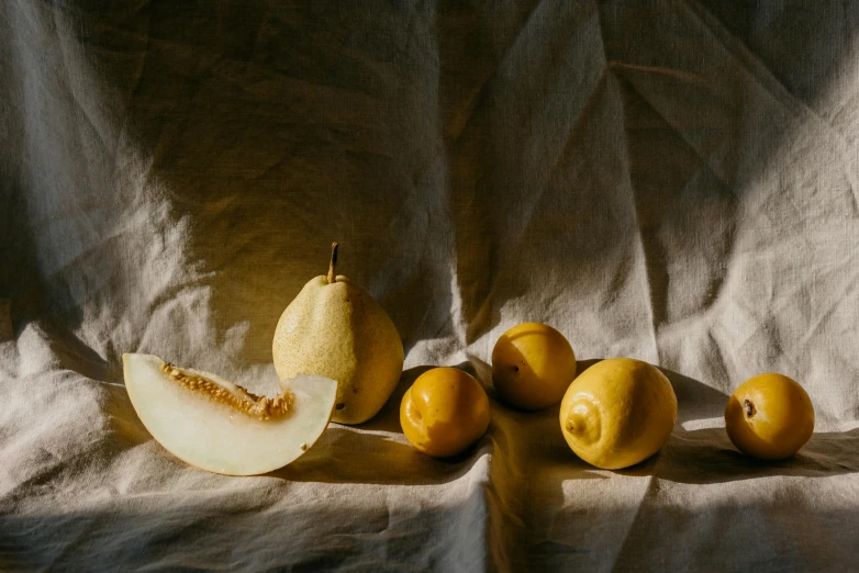 a group of fruit sitting on top of a table, inspired by Caravaggio, unsplash contest winner, yellowish light, linen canvas, 🐿🍸🍋, portrait photo