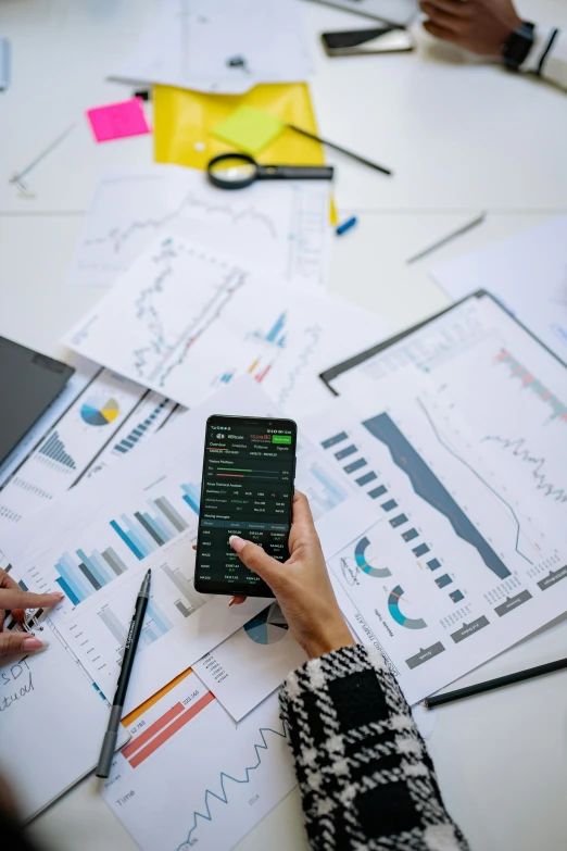 a group of people sitting around a table with papers and a cell phone, a picture, trending on pexels, analytical art, power bi dashboard, maths, 278122496, kai carpenter