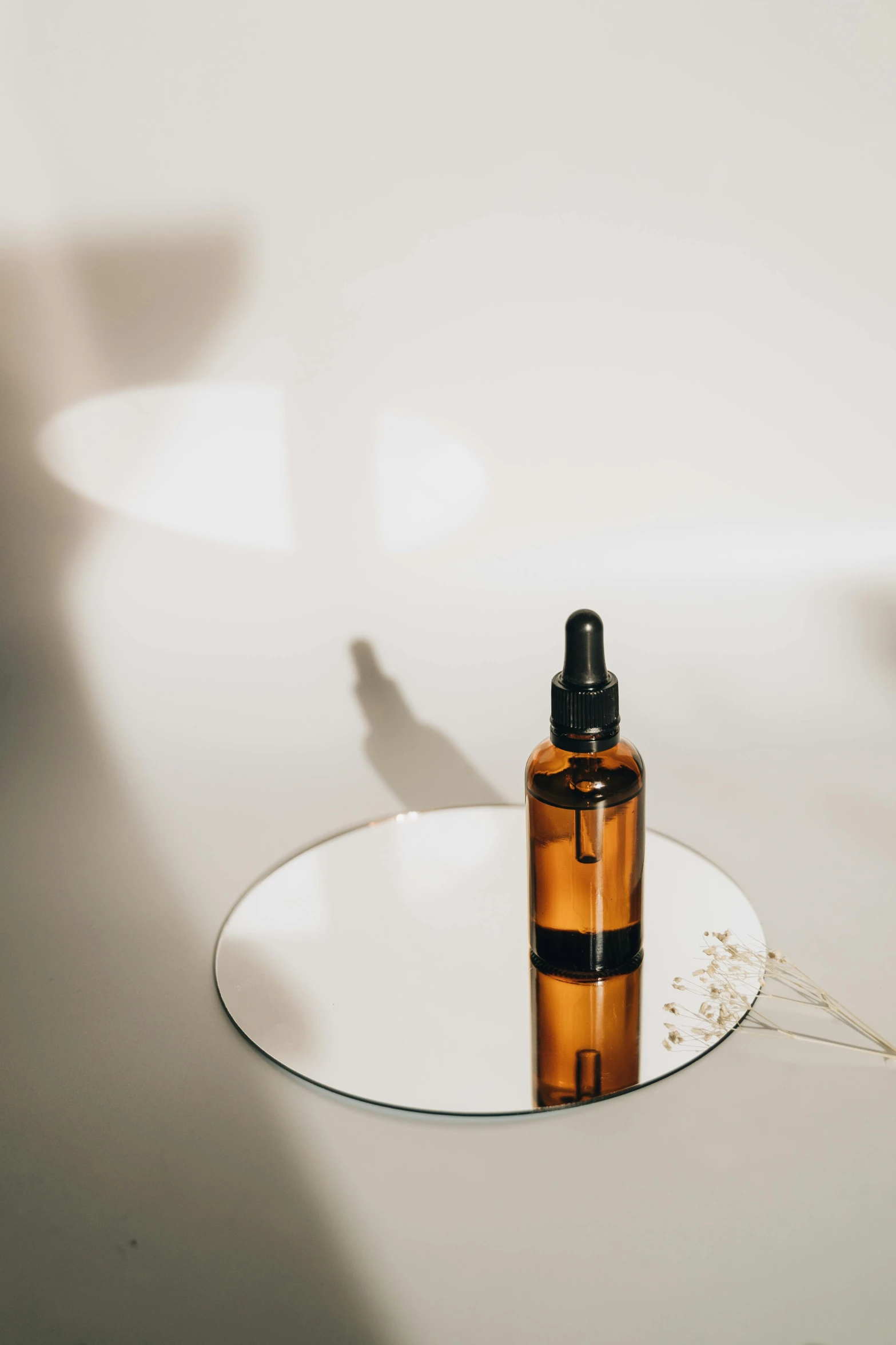 a bottle of liquid sitting on top of a white plate, by Will Ellis, trending on pexels, photoshoot for skincare brand, glowing amber, vials, back lit