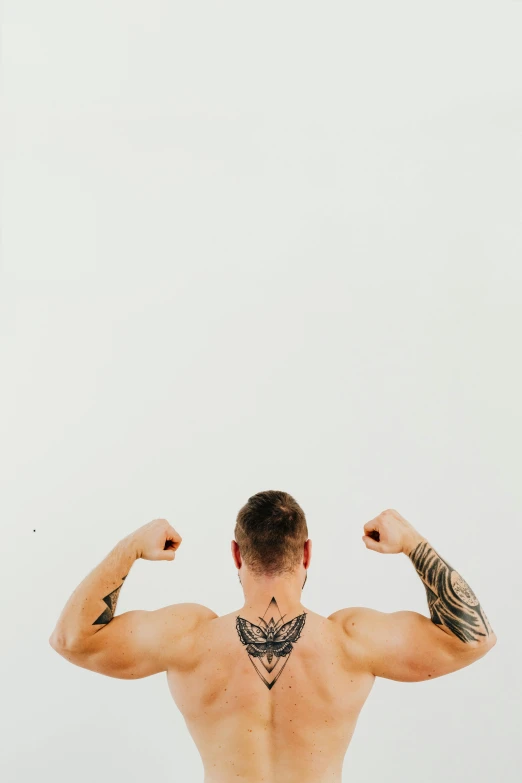 a man standing on top of a beach next to a surfboard, a tattoo, pexels contest winner, big biceps, in front of white back drop, profile image, tattooed back