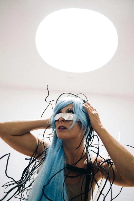 a woman with blue hair in a room, inspired by Taro Yamamoto, reddit, conceptual art, featuring wires, performing a music video, cosplay photo, {uncertain look}