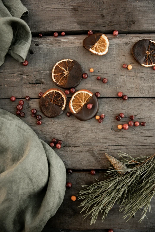 a wooden table topped with dried orange slices, by Jesper Knudsen, trending on unsplash, baroque, black fir, chocolate, linen, “berries