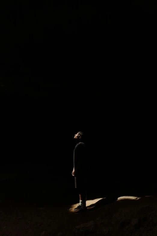 a person standing on a rock in the dark, a picture, by Caro Niederer, conceptual art, stage photography, tomohiro shimoguchi, dark. no text, yael shelbia