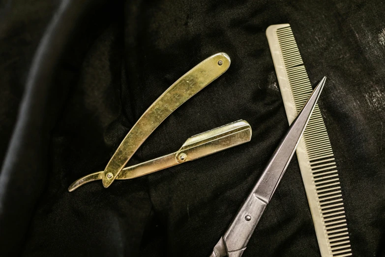 a pair of scissors and a comb on a black cloth, by Bradley Walker Tomlin, trending on pexels, renaissance, brass plated, small blond goatee, made of polished broze, thumbnail
