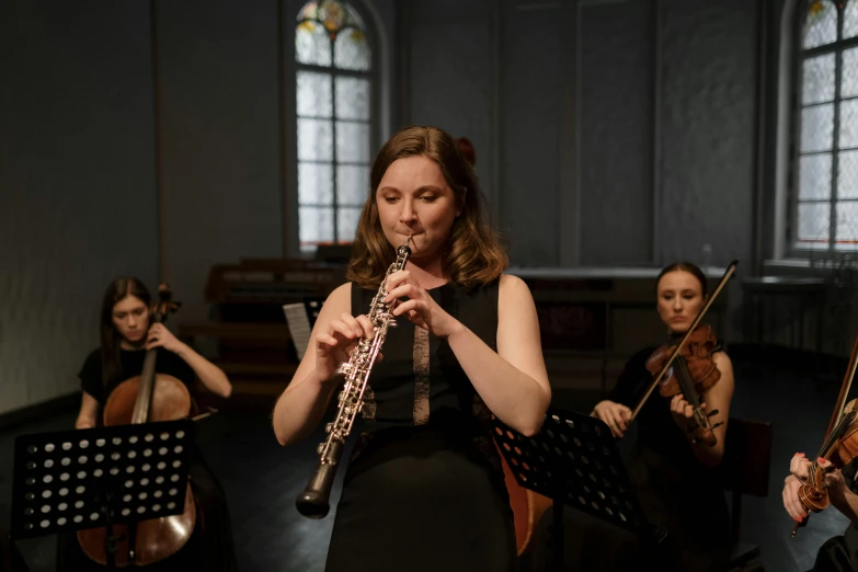 a woman in a black dress playing a flute, unsplash, baroque, trio, square, lachlan bailey, orthodox