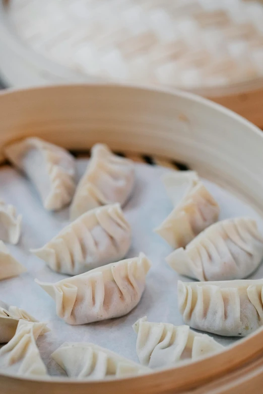 a bowl filled with dumplings sitting on top of a table, white horns, half image, new zealand, folded