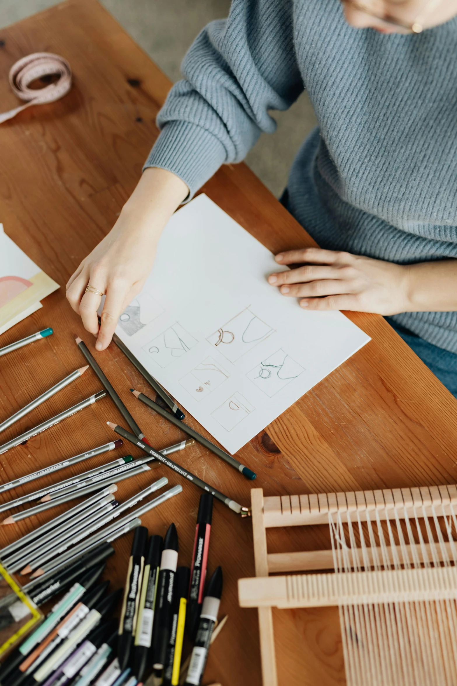 a woman sitting at a table working on a piece of paper, a drawing, trending on pexels, arbeitsrat für kunst, knolling, japanese collection product, art station front page, on a wooden desk