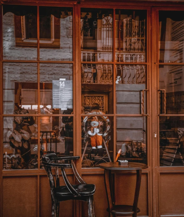 a couple of chairs sitting in front of a store, by Sebastian Spreng, pexels contest winner, arts and crafts movement, french door window, inside an old magical sweet shop, brown, doll house