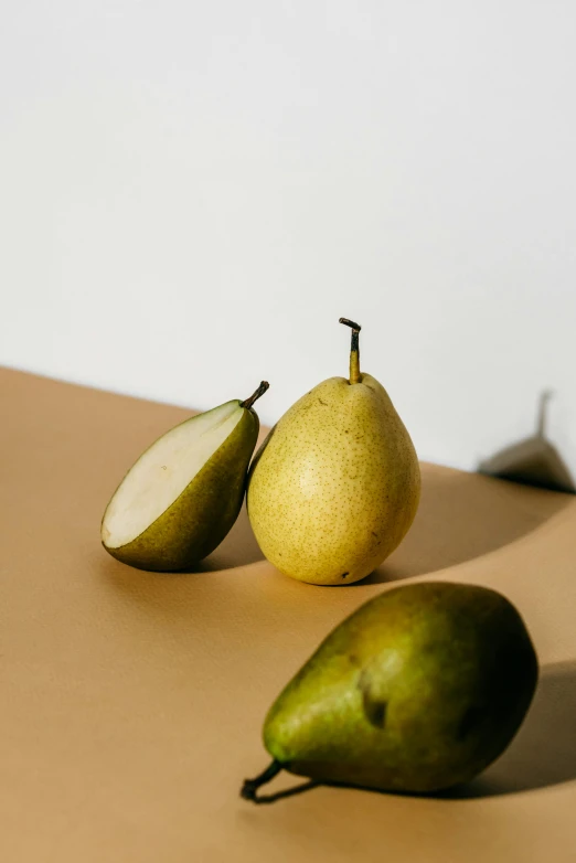 a couple of pears sitting on top of a table, trending on pexels, olive skin color, light from right, lulu chen, crisp image