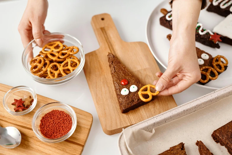 a wooden cutting board topped with pretzels and pretzels, a cartoon, by Julia Pishtar, trending on pexels, christmas, long shot from back, eating cakes, textured base ; product photos