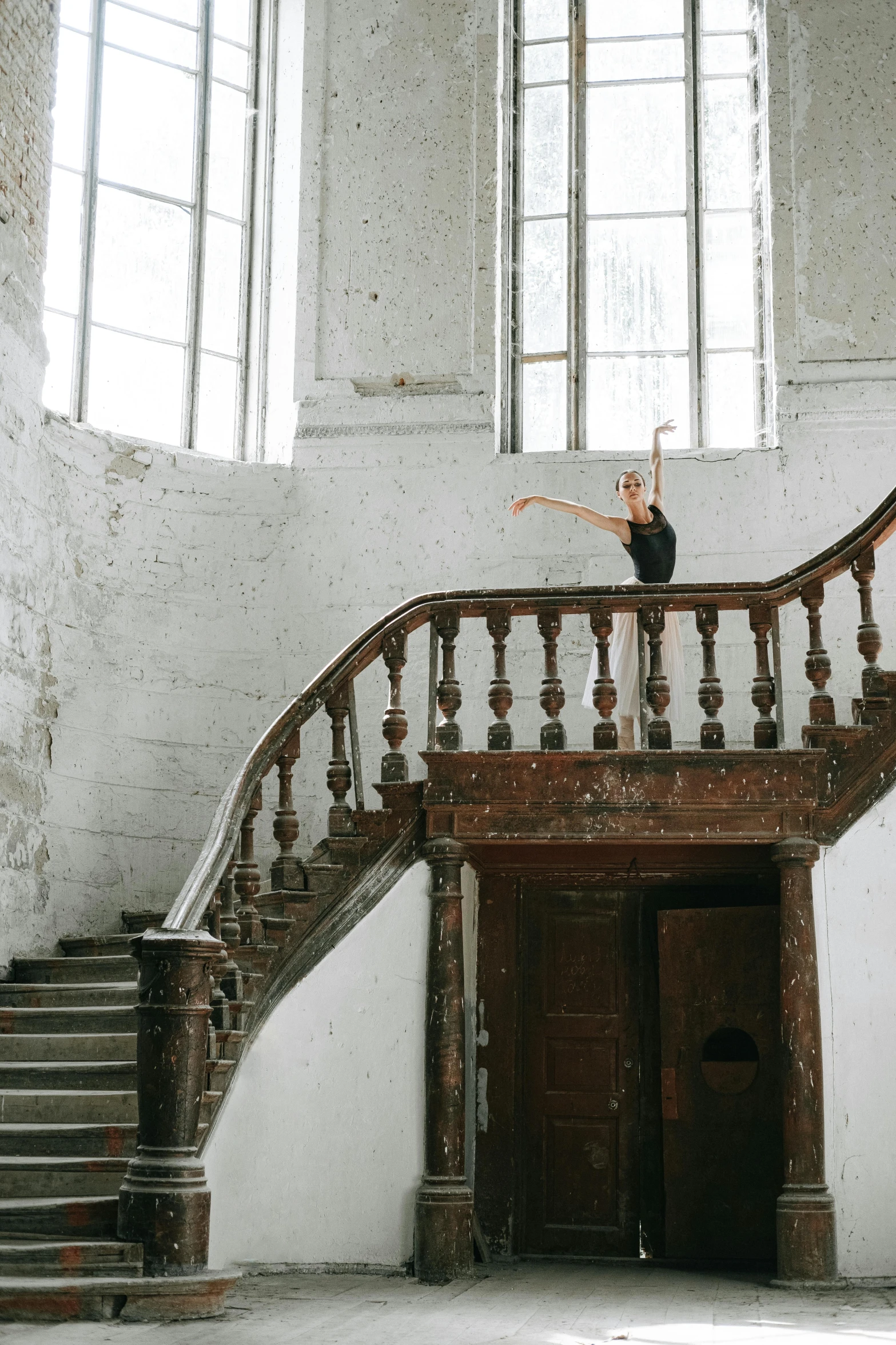 a woman standing at the top of a set of stairs, by Nina Hamnett, pexels contest winner, arabesque, inside a grand studio, choreographed, anna nikonova, an abandoned old