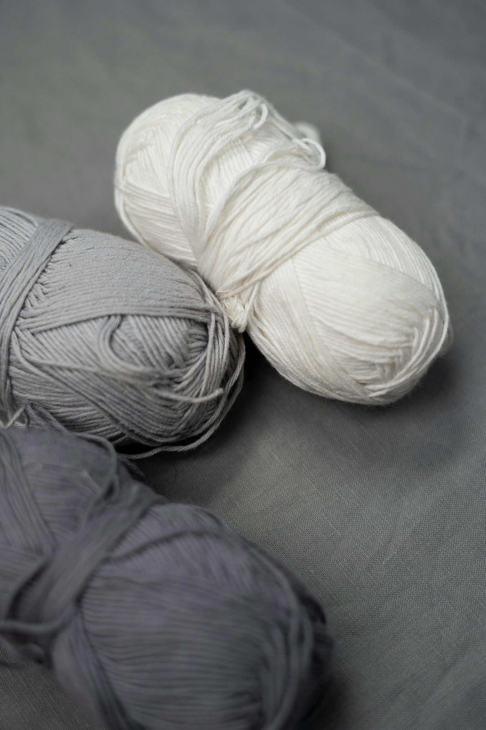 a couple of balls of yarn sitting on top of a table, white and grey, solid colours material, fineline detail, full product shot