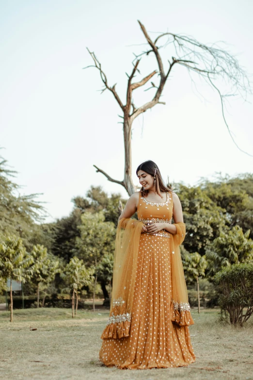 a woman in a yellow dress standing in a field, inspired by Saurabh Jethani, pexels contest winner, intricate details. front on, at the terrace, gold suit, orange hue