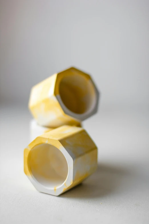 a couple of cups sitting on top of a table, dodecahedron, white and yellow scheme, studio product shot, emily rajtkowski