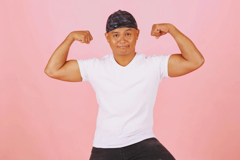 a man flexing his muscles on a pink background, inspired by Randy Vargas, trending on pexels, wearing baseball cap, in front of white back drop, androgynous person, george pemba