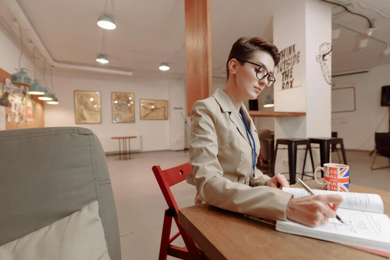 a woman sitting at a table writing on a piece of paper, wearing a suit and glasses, non binary model, art student, for hire 3d artist