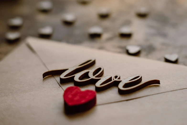 a red heart sitting on top of an envelope, by Daniel Lieske, pexels contest winner, letterism, laser cut, wooden, avatar image, calligraphy