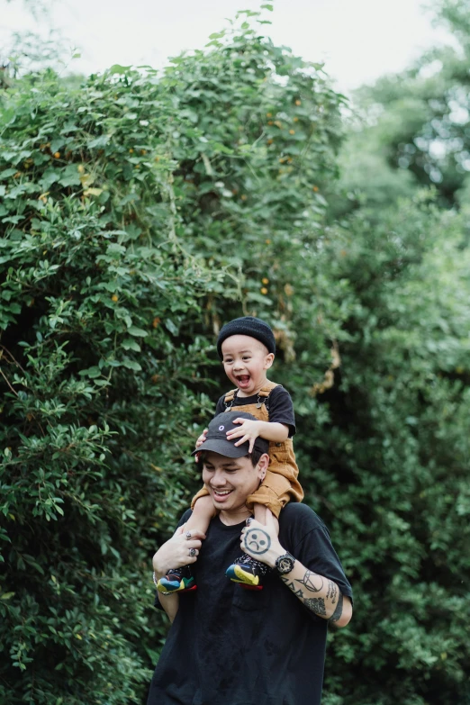 a man carrying a child on his shoulders, by Basuki Abdullah, unsplash, minimalism, amongst foliage, wearing skate helmet, square, happy friend