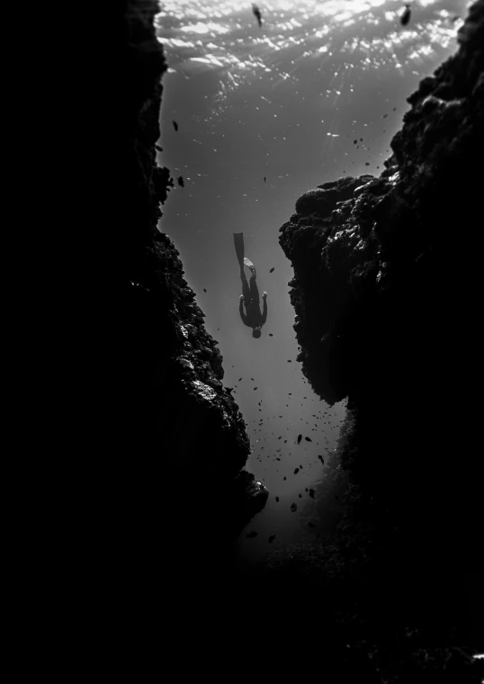 a black and white photo of a person swimming in a cave, a black and white photo, inspired by Michal Karcz, pexels contest winner, conceptual art, red sea, shadow depth, intricate environment - n 9, bottom of the ocean