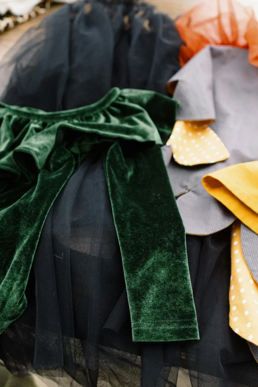 a table topped with lots of different colored napkins, by Nina Hamnett, trending on unsplash, renaissance, wearing a velvet cloak, black bow tie, yellow and greens, closeup - view