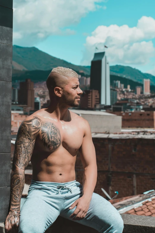 a shirtless man sitting on top of a building, an album cover, inspired by Randy Vargas, pexels contest winner, colombia, brown buzzcut, standing in a city center, profile image