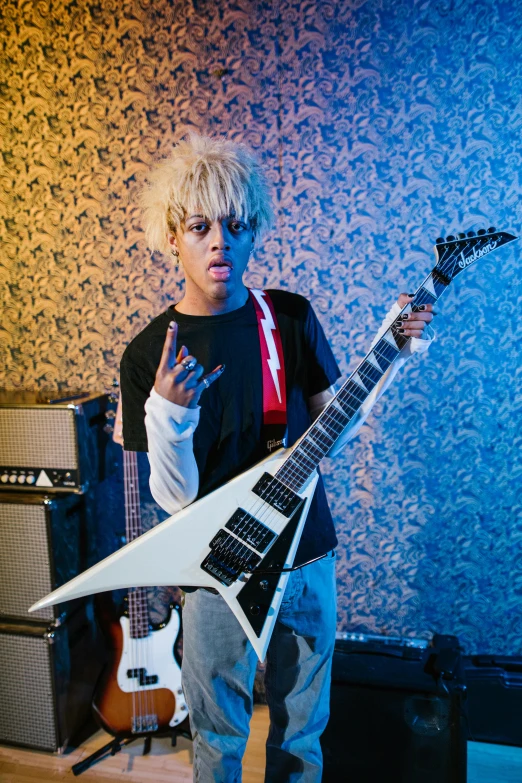 a person holding a guitar in a room, an album cover, inspired by Tadanori Yokoo, featured on reddit, vanitas, holding a silver electric guitar, ashteroth, intimidating pose, platinum blonde