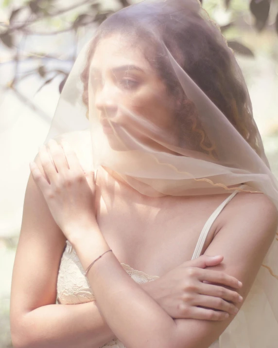 a woman in a wedding dress with a veil over her head, inspired by Elsa Bleda, trending on unsplash, renaissance, her skin is light brown, wearing translucent sheet, non binary model, holding intimately