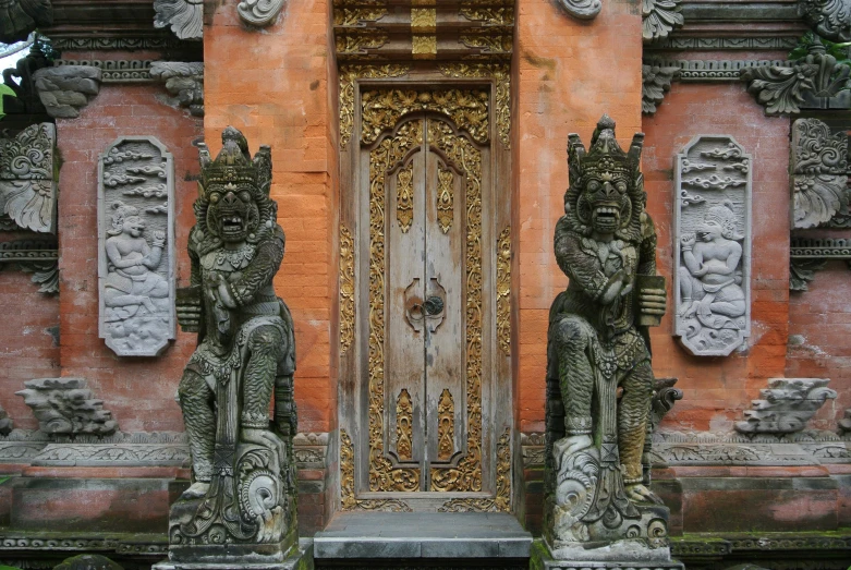 a couple of statues sitting in front of a door, inspired by I Ketut Soki, pexels contest winner, ornate carved architecture, thumbnail, tall door, puṣkaracūḍa