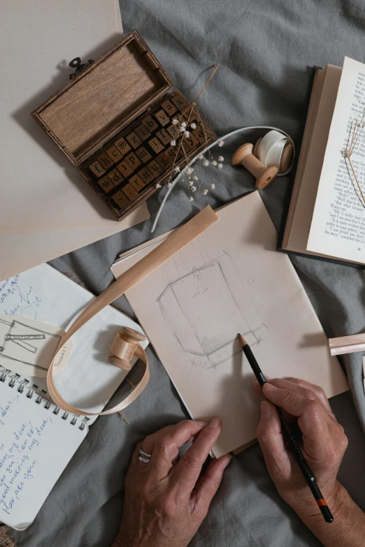 a person is drawing on a piece of paper, a drawing, inspired by Leonardo da Vinci, trending on unsplash, art & language, flatlay book collection, square shapes, with a wooden stuff, behance lemanoosh