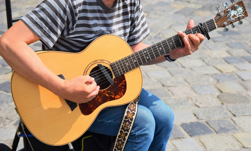 a man sitting on a chair playing a guitar, trending on pixabay, shin hanga, australian, zoomed in, 15081959 21121991 01012000 4k, street life