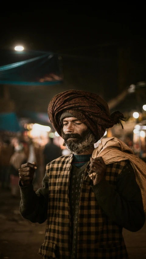 a man standing in the middle of a street at night, an album cover, inspired by Steve McCurry, unsplash contest winner, renaissance, turban, market, brown beard, tuareg