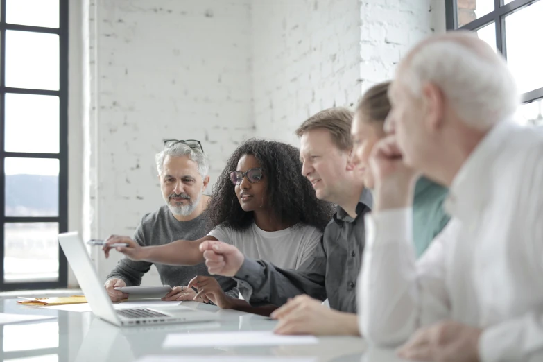 a group of people sitting around a table looking at a laptop, profile image, grey, diverse ages, corporate photo