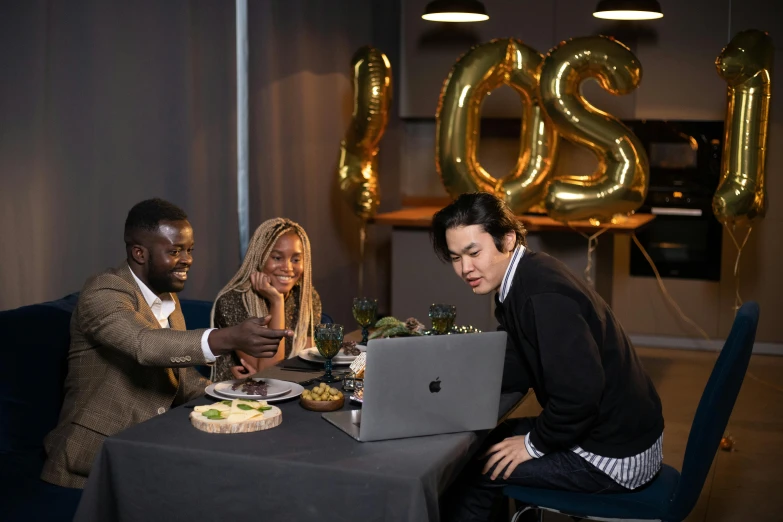 a group of people sitting around a table with a laptop, love os begin of all, celebrating a birthday, profile image, ignant