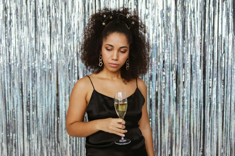 a woman in a black dress holding a glass of wine, pexels, hair jewellery, disappointed, disco party, mixed-race woman