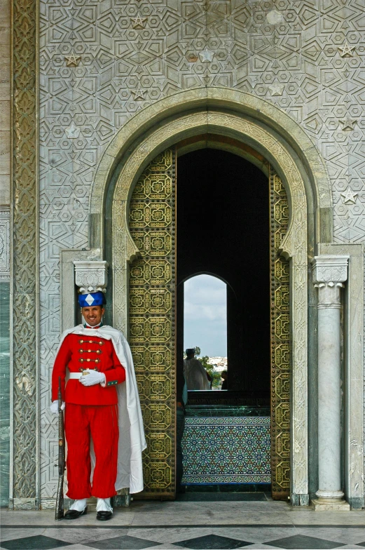 a man in a red uniform standing in front of a door, arabesque, moroccan tile archways, wearing a light grey crown, overlooking, officers uniform