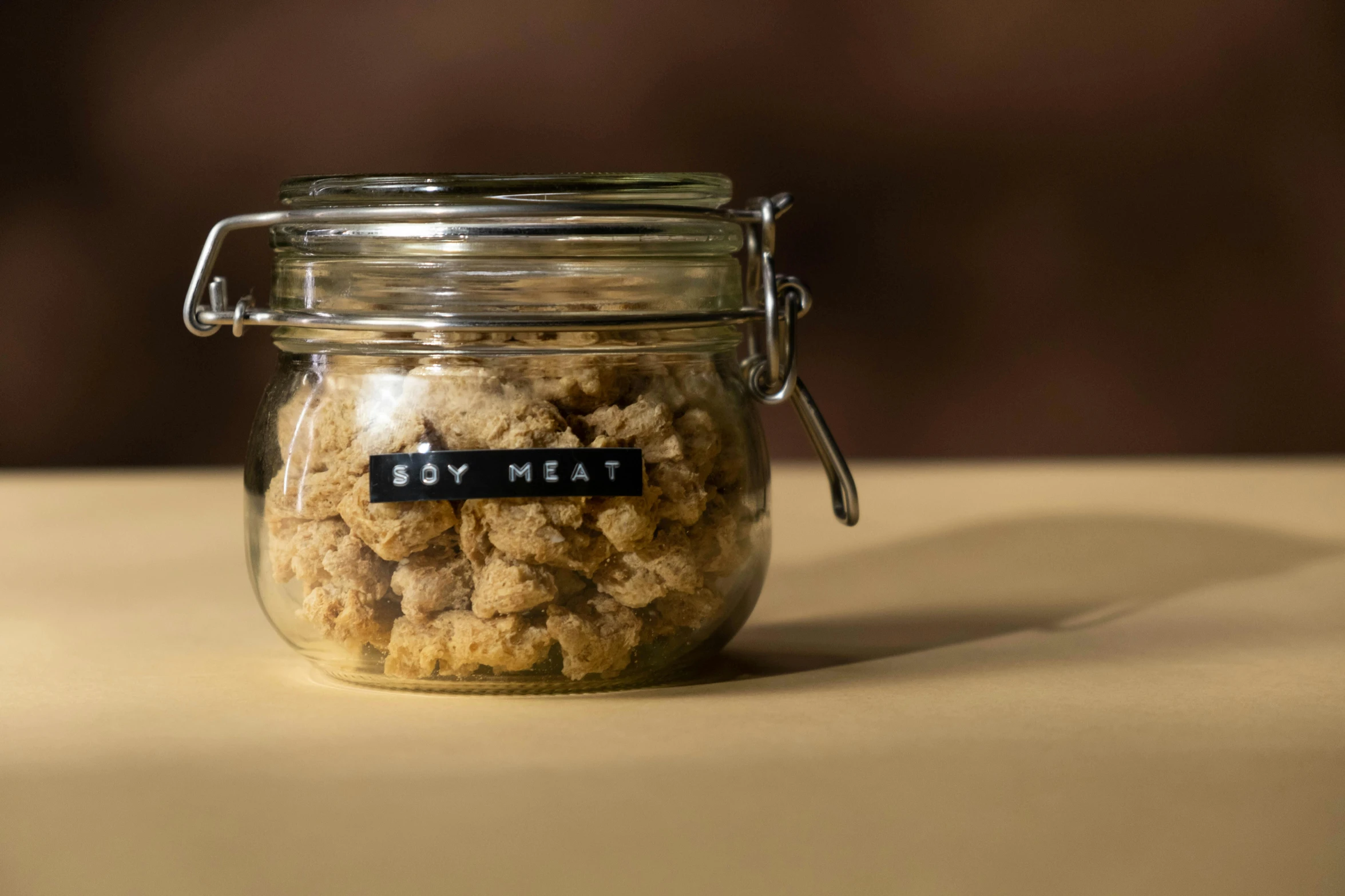 a jar filled with oatmeal sitting on top of a table, an album cover, pexels, meat texture, crispy, hey, small