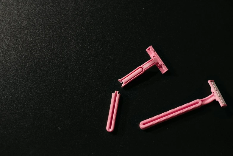 a couple of pink razors sitting on top of a black table, unsplash, plasticien, extended clip, thumbnail, disassembled, trending photo