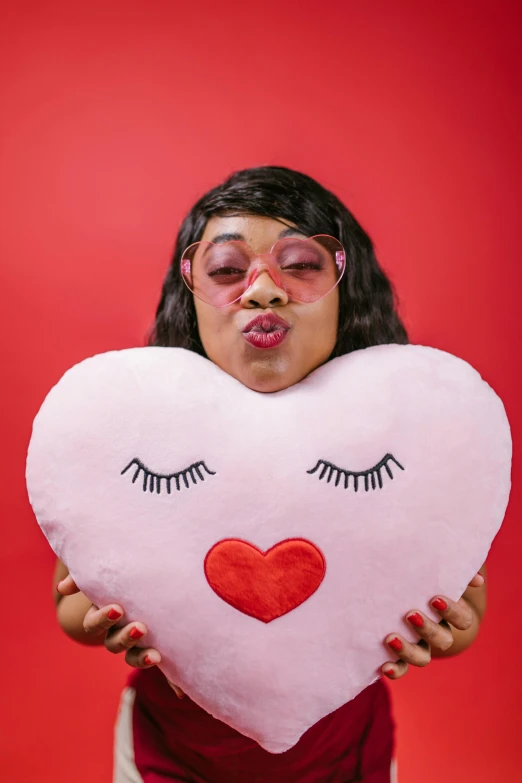 a woman holding a heart shaped pillow with eyelashes on it, non binary model, lizzo, fumo plush, gaunt cheeks