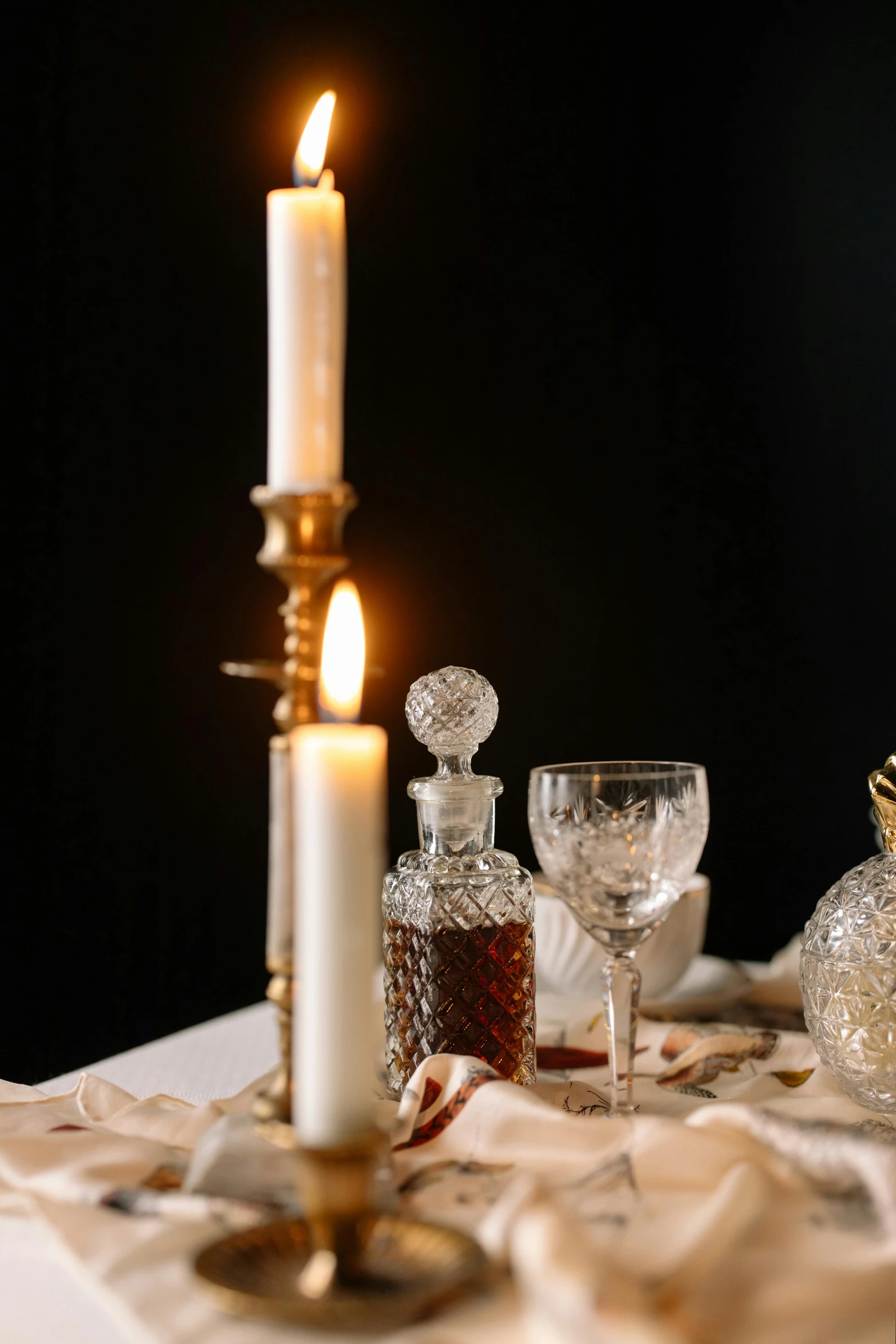 a candle that is sitting on a table, a still life, unsplash, baroque, glass and gold pipes, scene from a dinner party, studio photo, soft lighting |