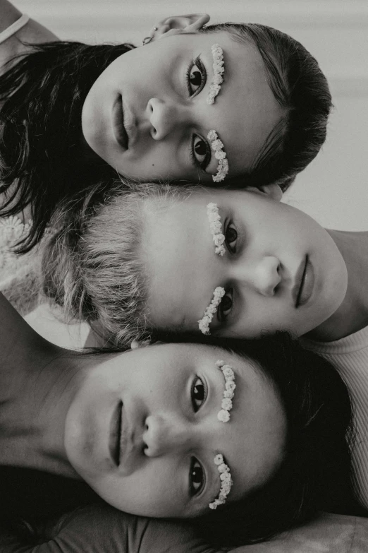 a couple of women laying on top of each other, a black and white photo, by Grace Clements, renaissance, white eyebrows, three women, bella poarch, with flowers