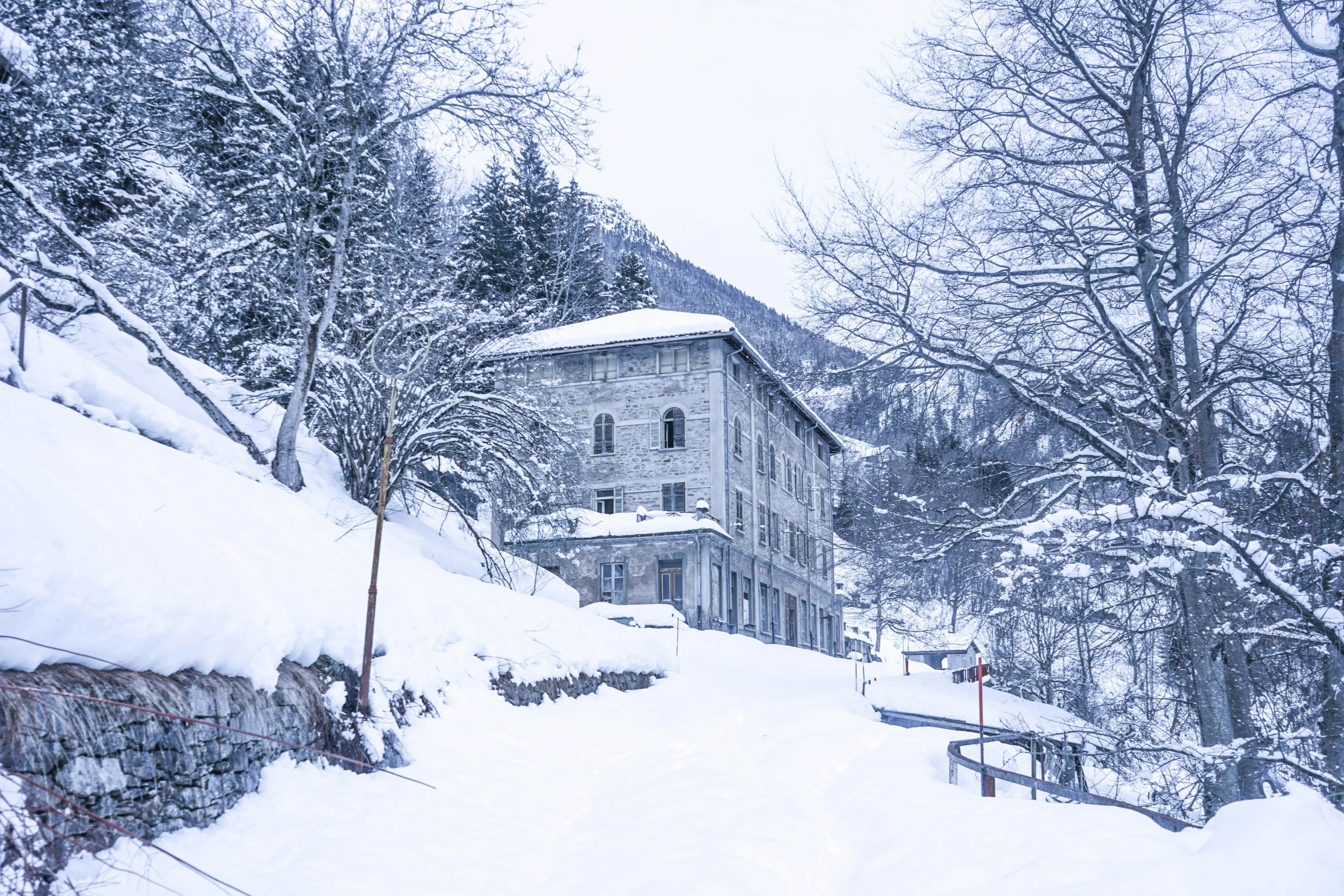 a man riding skis down a snow covered slope, inspired by Peter Zumthor, pexels contest winner, art nouveau, haunted gothic hotel, gray, exterior view, snowy italian road