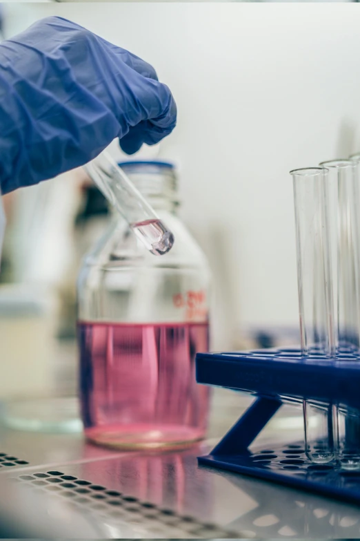 a person in a lab coat holding a test tube, pexels, pink and purple, silicon and carbon, glassware, pouring