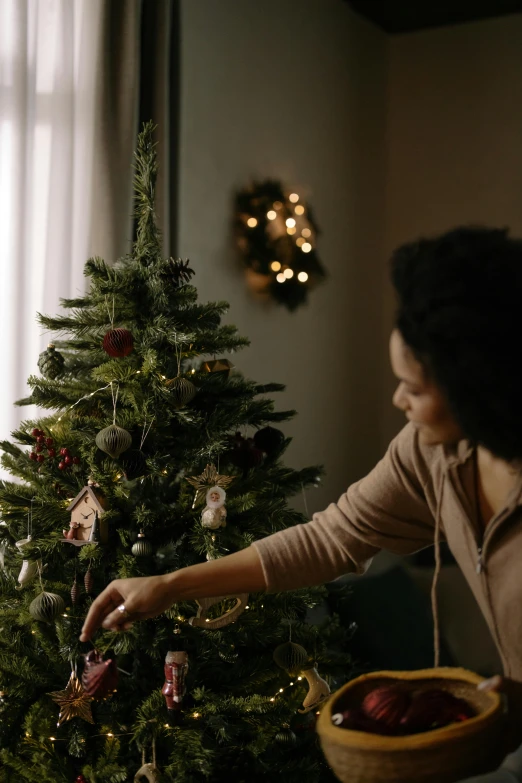 a woman decorating a christmas tree in a living room, a portrait, pexels contest winner, profile image, cinematic still, gif, first light