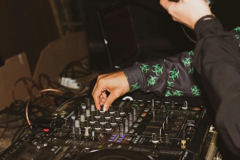 a close up of a person using a dj controller, by Julia Pishtar, trending on pexels, private press, mixing drinks, joints, holding green fire, casually dressed