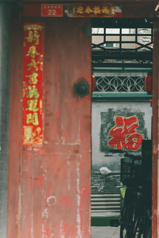 a red door with chinese writing on it, a silk screen, inspired by Cui Bai, pexels contest winner, graffiti, faded colors, mossy buildings, color picture, holiday