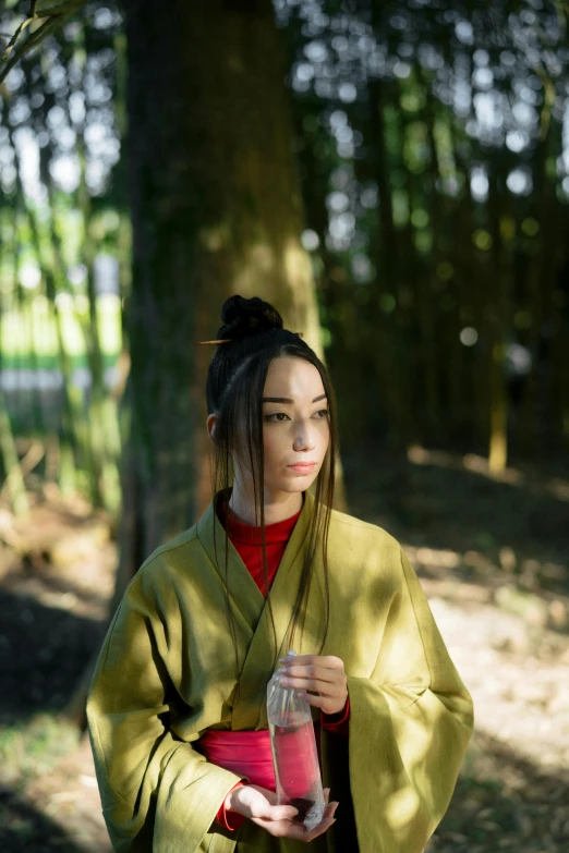 a woman in a kimono standing next to a tree, inspired by Gu An, unsplash, dressed in a green robe, ( ( theatrical ) ), made of bamboo, alessio albi