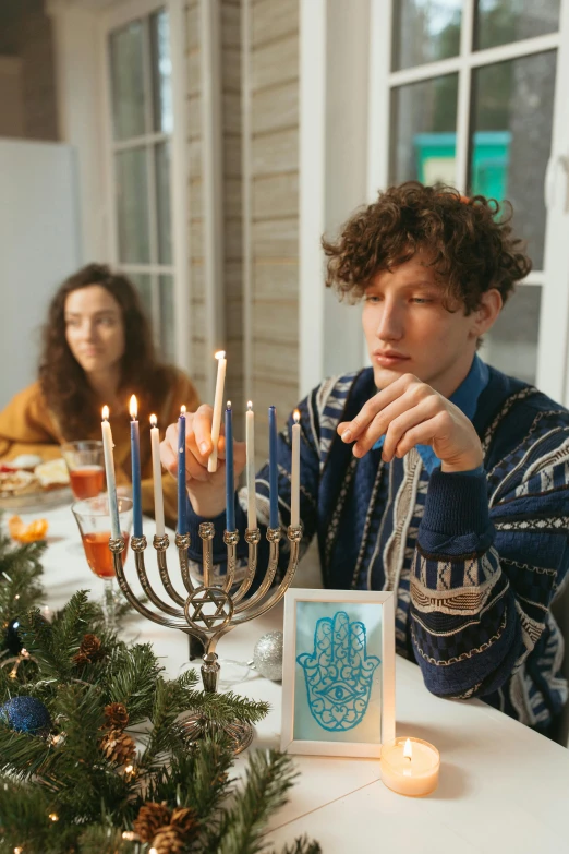 a man lighting a menorah at a dinner table, a colorized photo, pexels, renaissance, finn wolfhard, decorated ornaments, middle finger, hannah yata charlie immer