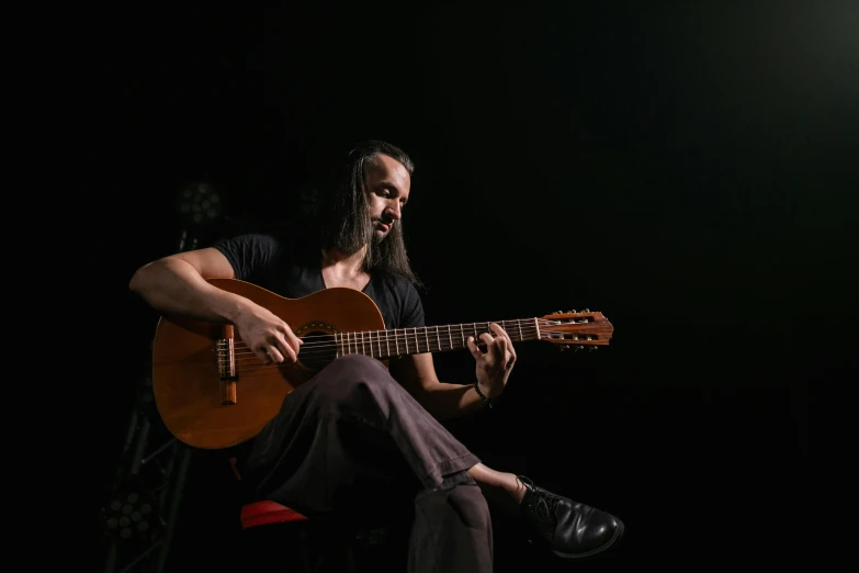 a man sitting on a chair playing a guitar, antipodeans, standing with a black background, monserrat gudiol, profile pic, 15081959 21121991 01012000 4k