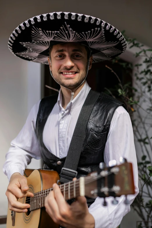 a man in a sombren playing a guitar, an album cover, inspired by Germán Londoño, face-on head shot, wearing authentic attire, while smiling for a photograph, professional image