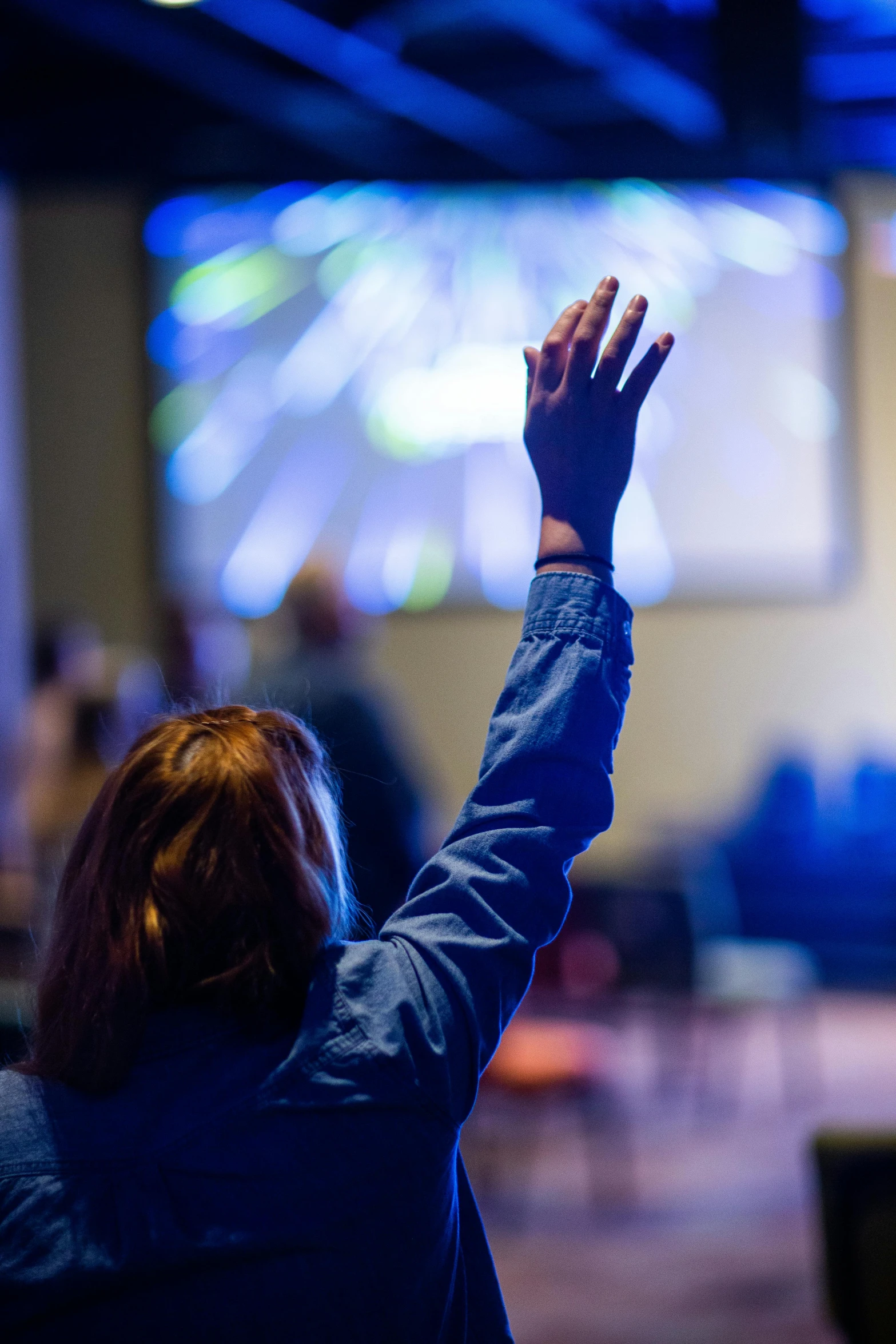 a woman raising her hands in front of a large screen, by Dan Content, church, college, paul barson, people at work